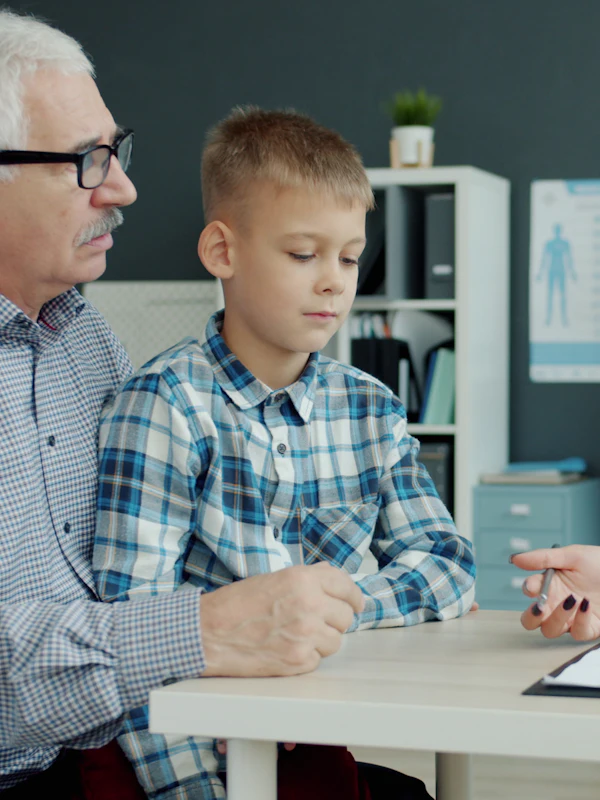 A grandfather and grandson talk with a provider at her desk